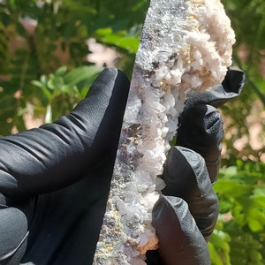 May include: A large, white, crystal cluster with a gray, metallic base. The cluster is composed of many small, pointed crystals.