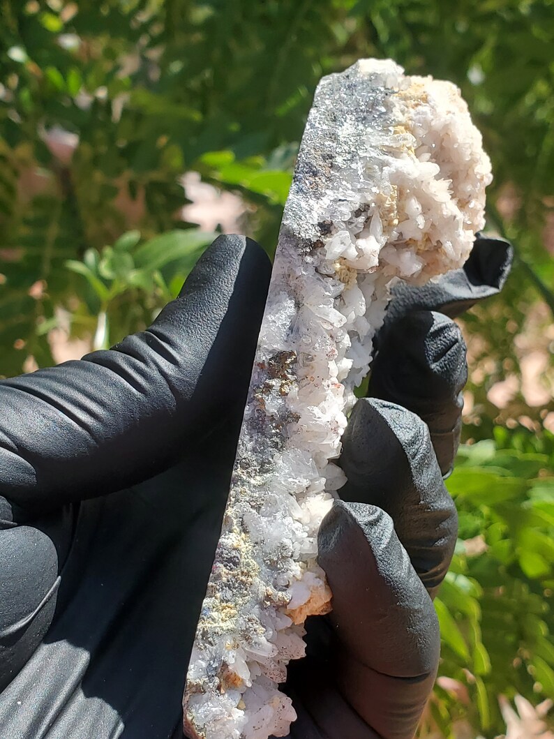 May include: A large, white, crystal cluster with a gray, metallic base. The cluster is composed of many small, pointed crystals.