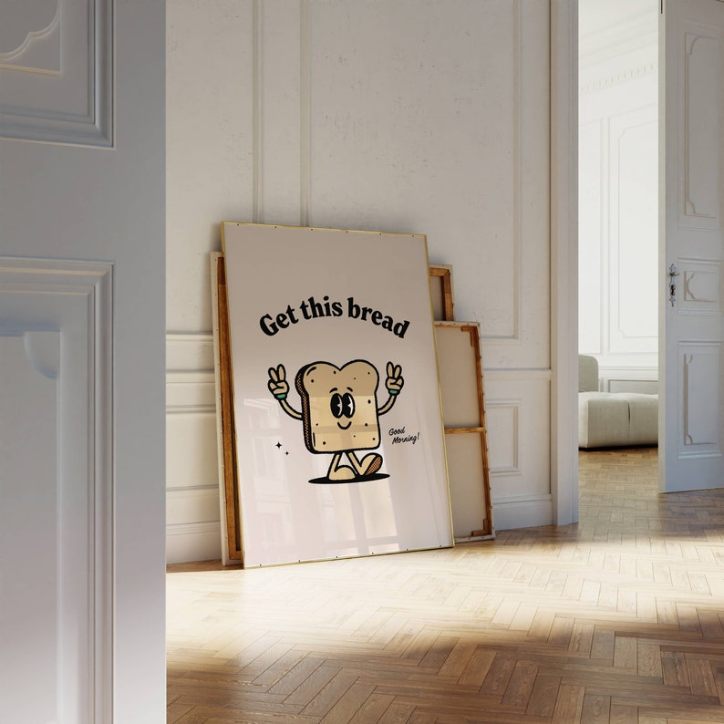 Puede incluir: Una impresi&oacute;n enmarcada en blanco con una ilustraci&oacute;n de dibujos animados de una rebanada de pan con brazos y piernas. El pan sonr&iacute;e y tiene el texto "Get this bread" arriba y "Good Morning!" abajo.