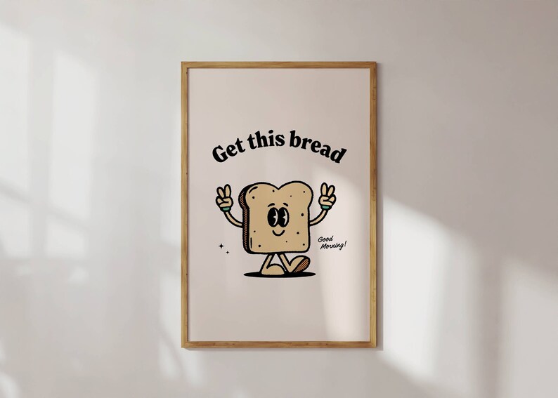 Puede incluir: Una impresi&oacute;n enmarcada con una ilustraci&oacute;n de dibujos animados de una rebanada de pan con brazos y piernas. El pan sonr&iacute;e y hace el signo de la paz con ambas manos. El texto "Get this bread" est&aacute; por encima del pan y el texto "Good Morning!" est&aacute; por debajo del pan.