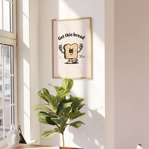 Puede incluir: Una impresi&oacute;n enmarcada con una ilustraci&oacute;n de dibujos animados de una rebanada de pan con una cara y el texto "Get this bread" y "Good morning!"