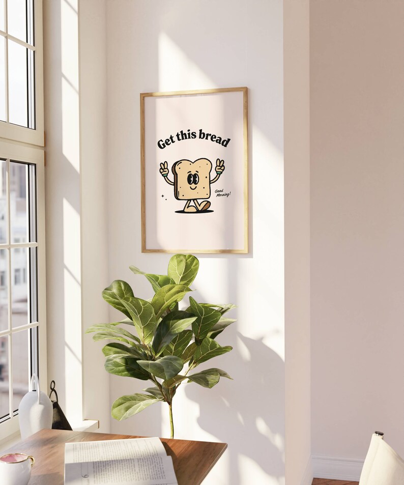 Puede incluir: Una impresi&oacute;n enmarcada con una ilustraci&oacute;n de dibujos animados de una rebanada de pan con una cara y el texto "Get this bread" y "Good morning!"