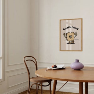 Puede incluir: Una ilustraci&oacute;n enmarcada de una rebanada de pan de dibujos animados con una cara sonriente y el texto "Get this bread" encima. El pan lleva gafas de sol y tiene un signo de paz en cada mano. El texto "Good Morning!" est&aacute; debajo del pan.