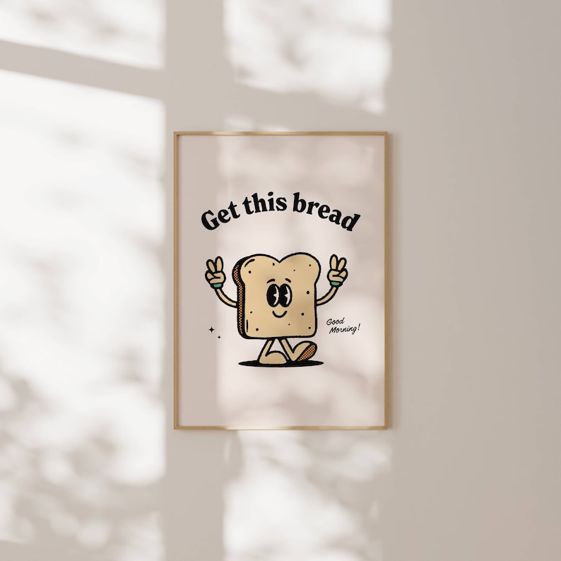 Peut inclure: Une impression encadrée blanche avec une illustration de dessin animé d'une tranche de pain avec un visage et des bras. Le pain fait le signe de la paix avec les deux mains. Le texte "Get this bread" est au-dessus du pain et le texte "Good Morning!" est en dessous du pain.