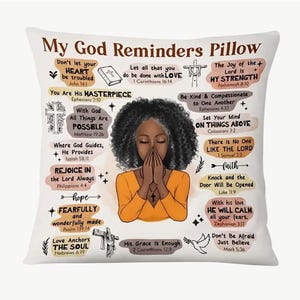 May include: A white pillow with a colourful design featuring a black woman praying. The pillow has inspirational quotes and bible verses in a handwritten style. The text includes phrases like "My God Reminders", "You Are His Masterpiece", "With God All Things Are Possible", "His Grace is Enough", and "Don't Let Your Heart Be Troubled".