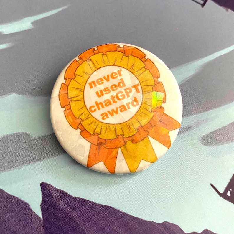 May include: A round, white button with the text "never used ChatGPT award" in orange. The text is centered within a yellow and orange ribbon design. The button is on a patterned surface.