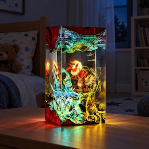 May include: A rectangular resin lamp featuring embedded miniature figures of Eevee and its evolutions, including Flareon, Vaporeon, and Jolteon. The clear resin block incorporates red, blue, and yellow lighting effects, creating a vibrant, illuminated display of these creatures within a rocky, textured landscape.