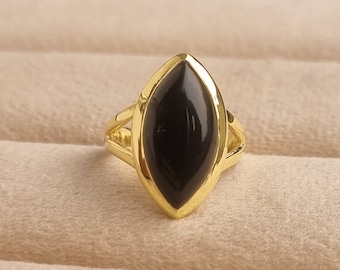May include: A gold ring with a black oval-shaped gemstone set in a gold setting.