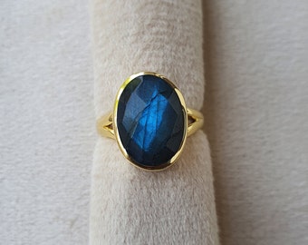 Könnte beinhalten: Ein goldener Ring mit einem großen ovalen blauen Labradorit-Edelstein.