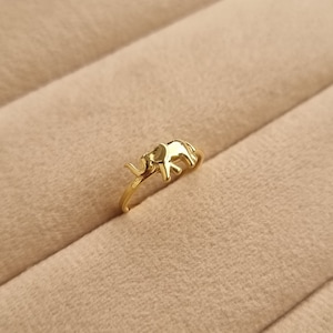 May include: A gold-colored ring with an elephant design. The elephant is facing to the right and has its trunk raised.