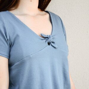 Puede incluir: Primer plano de un top azul de canal&eacute; con un detalle anudado en el escote.