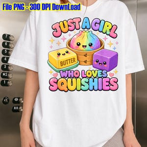 Puede incluir: Una camiseta blanca con un gráfico colorido de una bola de masa arcoíris, un bloque amarillo etiquetado como BUTTER y un cubo morado con caras sonrientes. El texto dice JUST A GIRL WHO LOVES SQUISHIES en una fuente de burbujas multicolor.