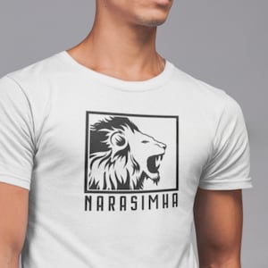 May include: White t-shirt featuring a black and white graphic of a roaring lion inside a black rectangle. The word "NARASIMHA" is printed in a bold, sans-serif font below the graphic. The shirt is made of a soft, comfortable material.