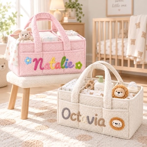 May include: Two rectangular, textured fabric storage caddies with handles and exterior pockets. The pink caddy features the name Natalie in colorful yarn lettering with flower accents. The cream caddy features the name Octavia and a lion face.
