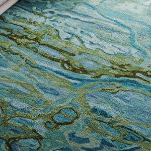 May include: Abstract area rug with a blue and green marbled pattern. The rug has a soft, textured surface.