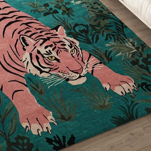 May include: A rectangular area rug featuring a large pink tiger with black stripes positioned in a prowling stance. The tiger is set against a deep teal background filled with dark green foliage and leaf patterns, creating a high-contrast design.