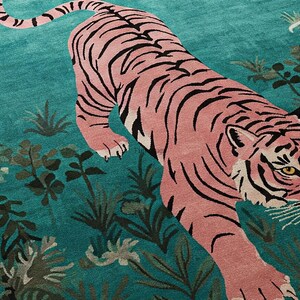 May include: A rectangular area rug featuring a large pink tiger with black stripes positioned diagonally across a vibrant teal background. The design includes dark green botanical foliage and plants scattered throughout the field.