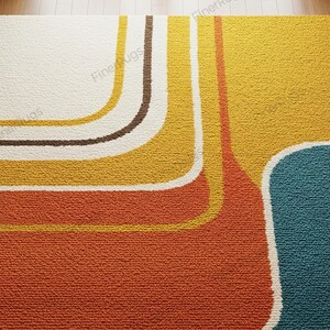 May include: A close-up of a retro-style rug with a textured surface. The rug features a color block design with orange, yellow, brown, and teal sections. White outlines define the curved shapes.