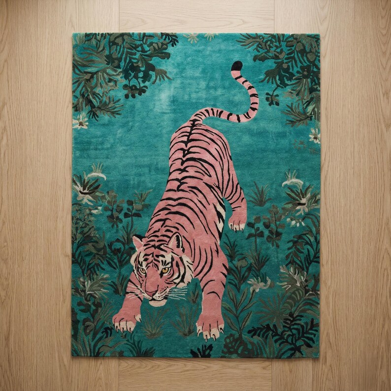 May include: A rectangular area rug featuring a pink tiger with black stripes positioned in the center. The background is a vibrant teal color decorated with dark green foliage, leaves, and small white flowers surrounding the tiger.