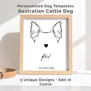 May include: A framed print with a minimalist black and white illustration of an Australian Cattle Dog's ears and a heart. The dog's name, "Red", is written in cursive below the heart. The text "my heart dog" is below the name. The frame is light brown.