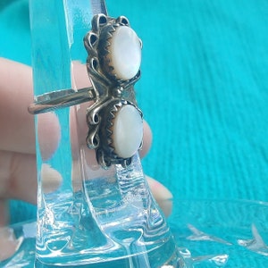 May include: A silver ring with two white mother-of-pearl stones set in ornate silver settings.
