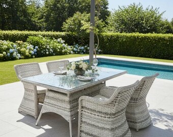 May include: Outdoor dining set with a square glass-topped table and four matching wicker chairs. The light gray furniture is arranged on a patio near a swimming pool, with a garden backdrop.