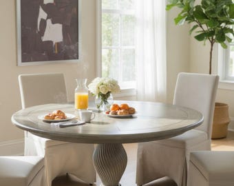 May include: A circular dining table with a grey finish, set for a meal. The table is surrounded by four upholstered chairs and a matching ottoman. A vase of flowers, juice, and pastries are on the table. An abstract artwork hangs on the wall.