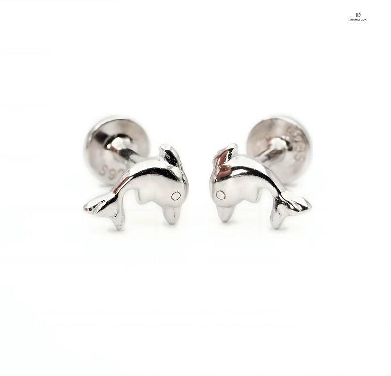 May include: A pair of silver stud earrings featuring a dolphin design. The earrings are small and delicate, perfect for everyday wear.