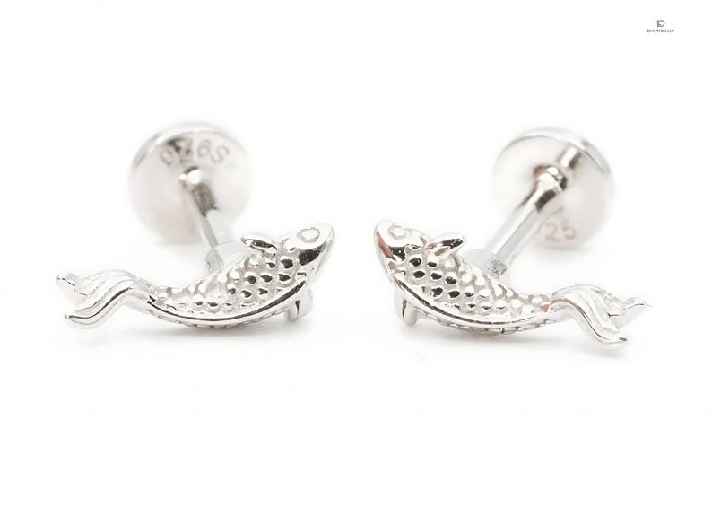May include: A pair of silver fish stud earrings. The fish are detailed with a textured surface and have a silver post and butterfly backing.