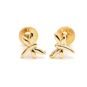 May include: A pair of gold-toned stud earrings featuring a polished dragonfly design. Each earring has a smooth, reflective surface and a flat circular backing. The dragonfly motif is centered on the post, showcasing delicate wings and a body.