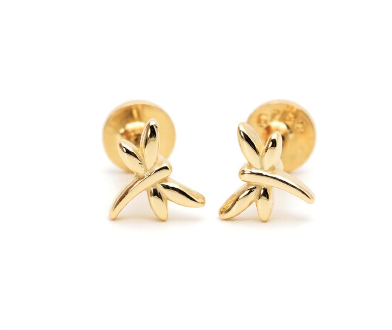 May include: A pair of gold-toned stud earrings featuring a polished dragonfly design. Each earring has a smooth, reflective surface and a flat circular backing. The dragonfly motif is centered on the post, showcasing delicate wings and a body.