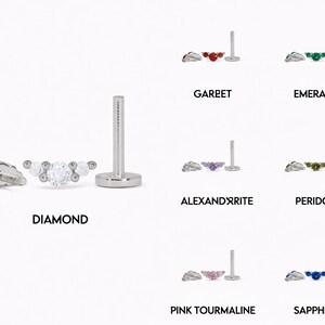 Op de afbeelding: Een zilverkleurige oorbel met platte achterkant en een gebogen staafje met drie ronde stenen. De set toont diverse edelsteenopties met de labels Diamond, Garnet, Emerald, Alexandrite, Peridot, Pink Tourmaline en Sapphire, elk met een stift.