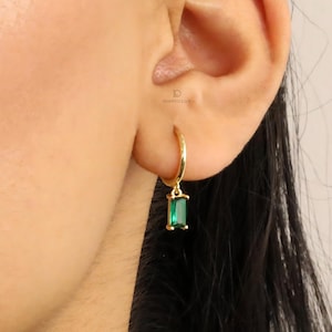 Puede incluir: Aretes de aro de oro con una piedra rectangular verde esmeralda colgante.