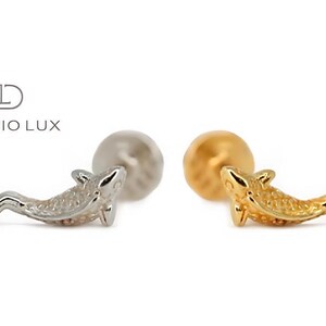 May include: Two gold and silver dolphin shaped earrings. The earrings are on a white background.