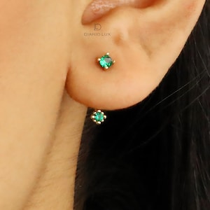 May include: A pair of gold earrings with green gemstone accents. The earrings are small and delicate, and they would make a great gift for a special occasion.