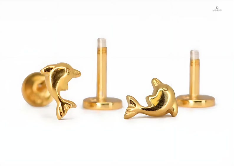 May include: Two gold dolphin stud earrings with a post and a flat back. The dolphins are facing the same direction and are in a jumping pose.