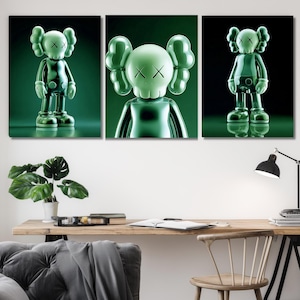 May include: A triptych artwork showcasing green, glossy figures with X-shaped eyes. The figures stand with rounded ears and a reflective surface. The artwork is displayed above a wooden desk with a plant and a lamp.