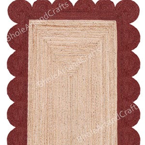 May include: A rectangular jute rug with a scalloped burgundy border. The inner section of the rug is a natural beige colour, with a woven texture. The border is a darker shade of red. The rug is suitable for home decor.