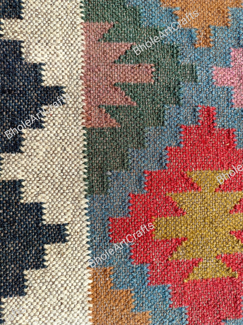 May include: A close-up of a colorful woven rug with geometric patterns in shades of red, blue, green, brown, and beige. The rug is made of natural fibers and has a textured surface.