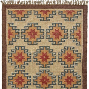 May include: A beige rug with a geometric pattern of red, orange, and blue stars. The rug has a brown fringe border.