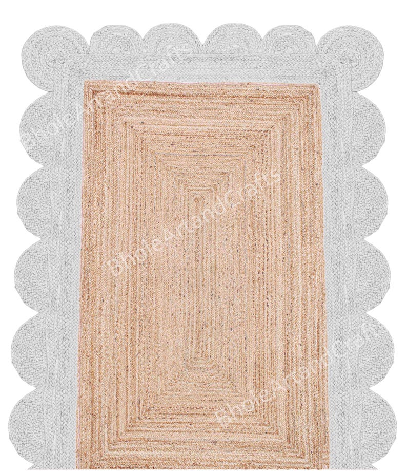 May include: Rectangular jute rug with a light brown centre and a white scalloped border. The rug has a woven texture and a neutral colour palette, suitable for various interior styles. The rug is designed for indoor use.