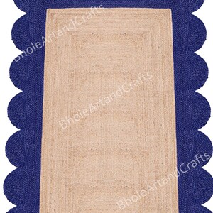 May include: A rectangular jute rug with a navy blue scalloped border. The rug's central area is a natural beige colour, and the border adds a decorative element. The rug is suitable for indoor use.