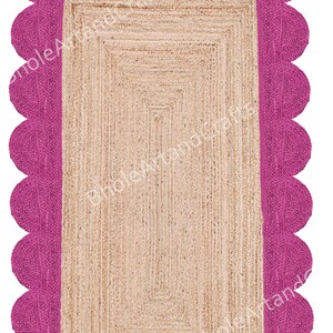 May include: A rectangular jute rug with a fuchsia scalloped border. The centre of the rug has a natural beige colour and a rectangular design. The rug is made of woven jute fibres.