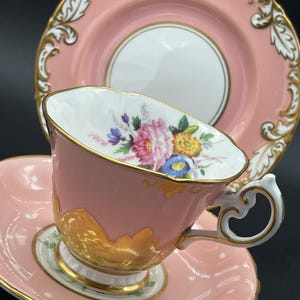 Può includere: Un set di tazza da tè, piattino e piatto rosa. La tazza e il piattino sono decorati con pois bianchi. La tazza presenta un motivo floreale all'interno e dettagli dorati. Il piatto ha un centro bianco e un bordo dorato.