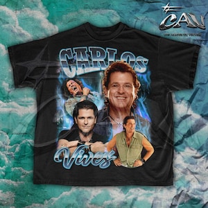 Puede incluir: Camiseta negra con un estampado gráfico de Carlos Vives. El gráfico presenta un diseño de llamas azules y blancas con imágenes de Carlos Vives y el texto "Carlos Vives".