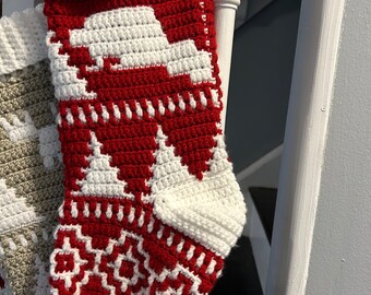 May include: A red and white crocheted Christmas stocking with a white snowflake design. The stocking is hanging on a white banister.