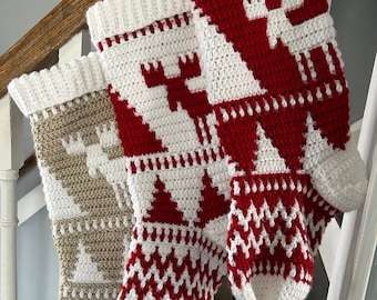 May include: Three handmade Christmas stockings, crocheted with white, red, and beige yarn. Each stocking features a different festive design, including a moose, Christmas trees, and geometric patterns. The stockings are displayed on a wooden staircase.