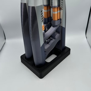 May include: A 3D printed display stand with three gray and black 3D printed objects. The objects are hollow and have a copper colored interior.
