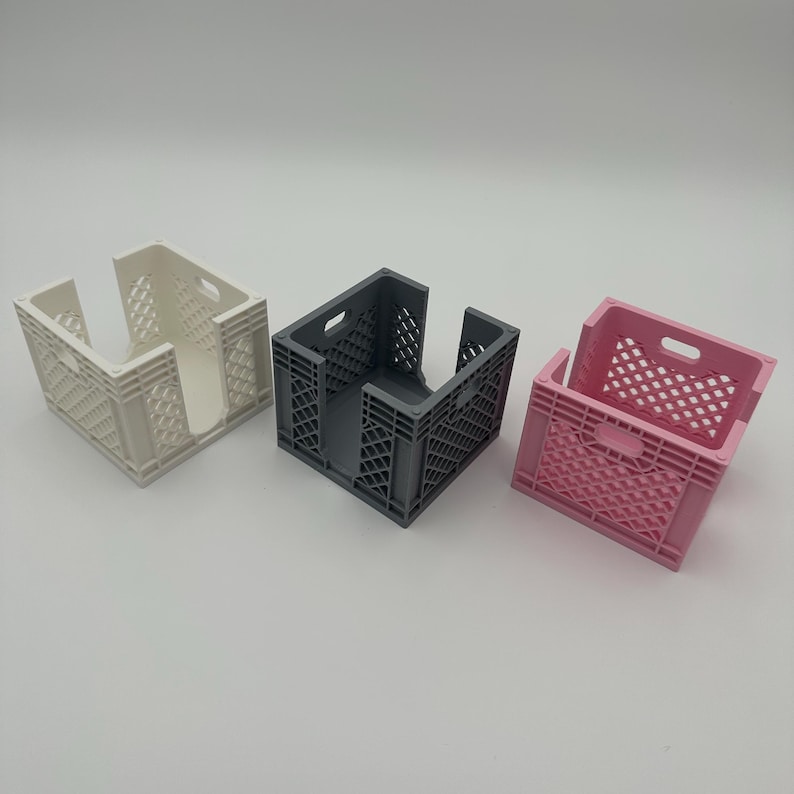 May include: Three empty crate-style organizers in white, gray, and pink. The organizers are made of plastic and have a grid pattern.