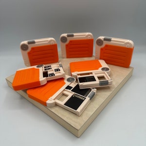 May include: Five orange and white plastic cases with a variety of compartments for storing small items. The cases are open and arranged on a light brown surface.